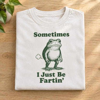 Folded white Comfort Colors tee with Sometimes I Just Be Fartin frog print