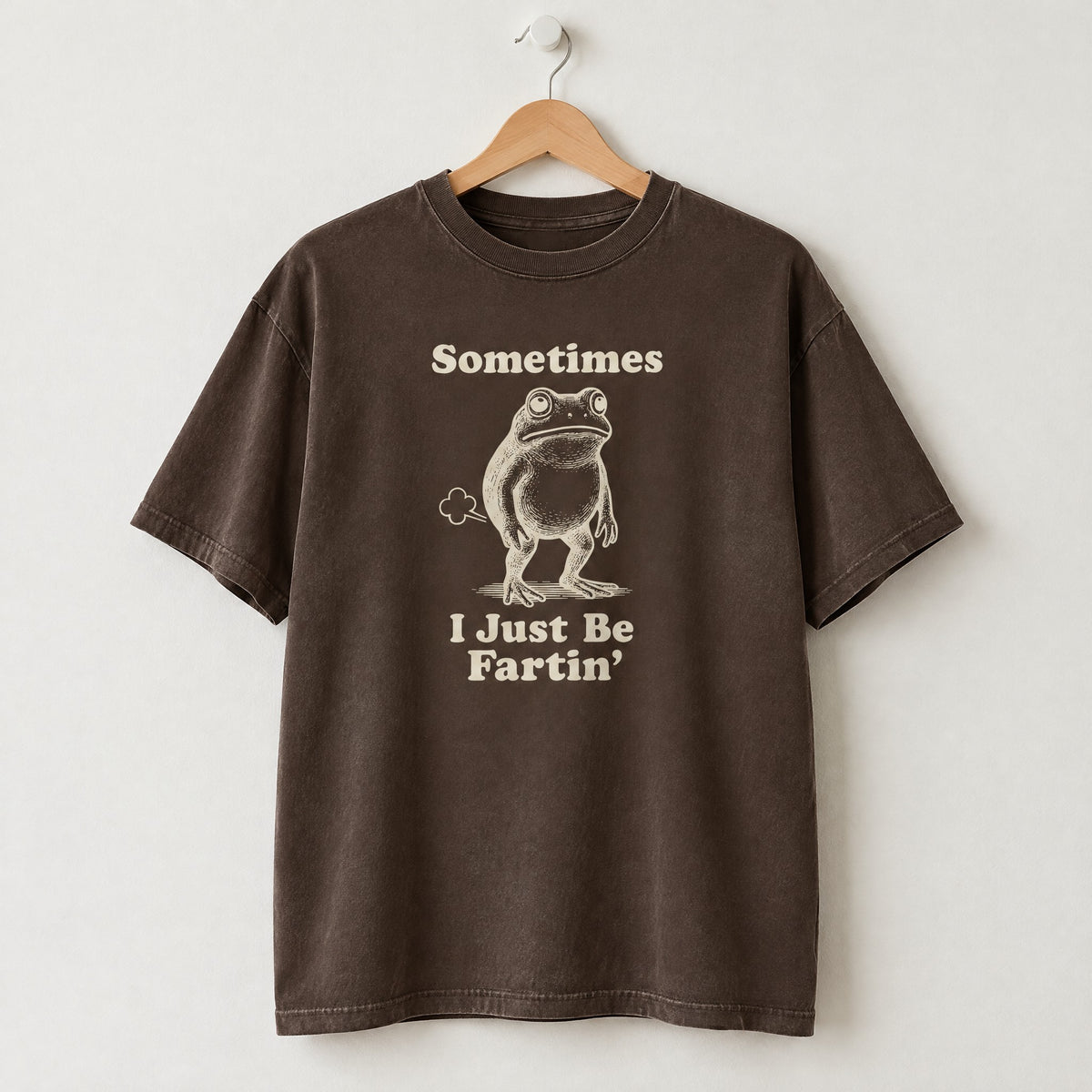 Espresso Comfort Colors shirt on a hanger with Sometimes I Just Be Fartin frog design