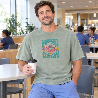 Male nurse wearing a Sage Comfort Colors Wound Care Crew shirt holding coffee in a hospital cafeteria