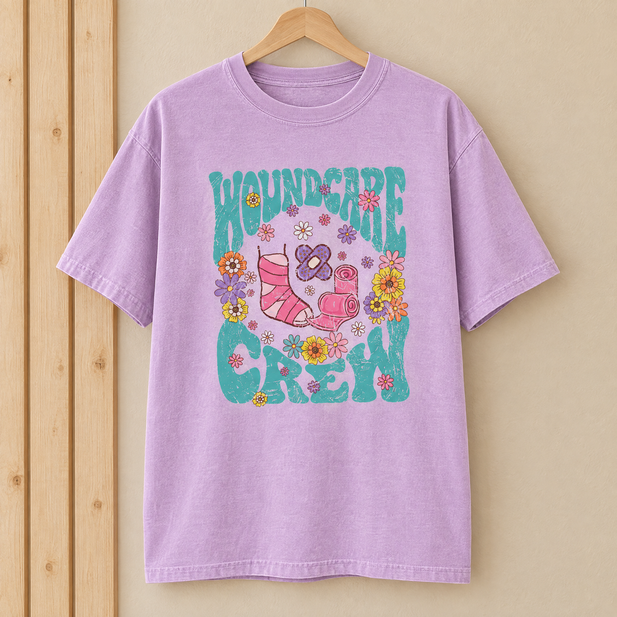 Wound Care Crew Comfort Colors shirt in Orchid on a wooden hanger