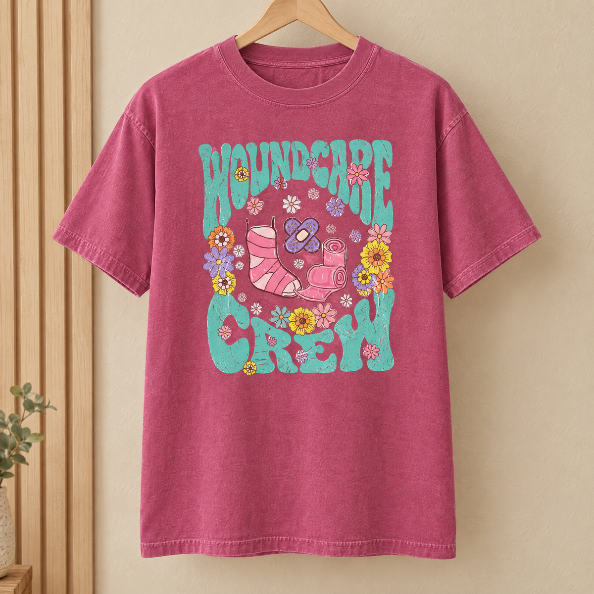 Wound Care Crew Comfort Colors shirt in Berry on a wooden hanger