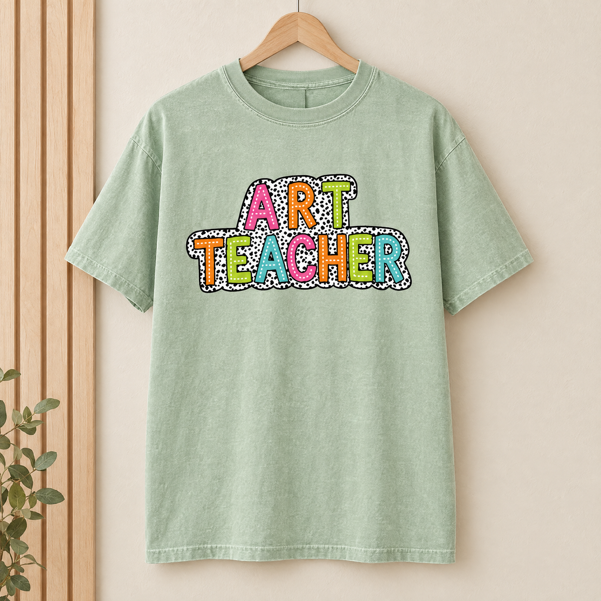 Art Teacher Comfort Colors shirt in Light Green on a wooden hanger