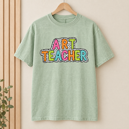 Art Teacher Comfort Colors shirt in Light Green on a wooden hanger