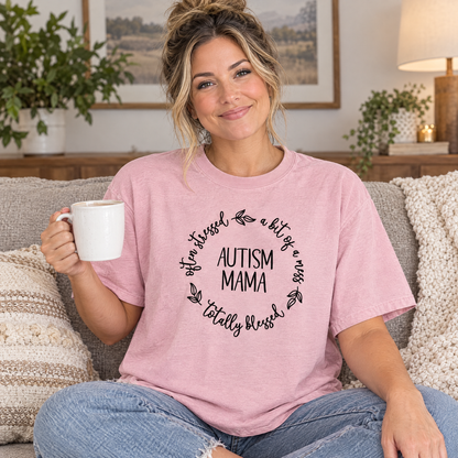 Mom wearing a Blossom pink Comfort Colors Autism Mama shirt on a cozy couch with coffee