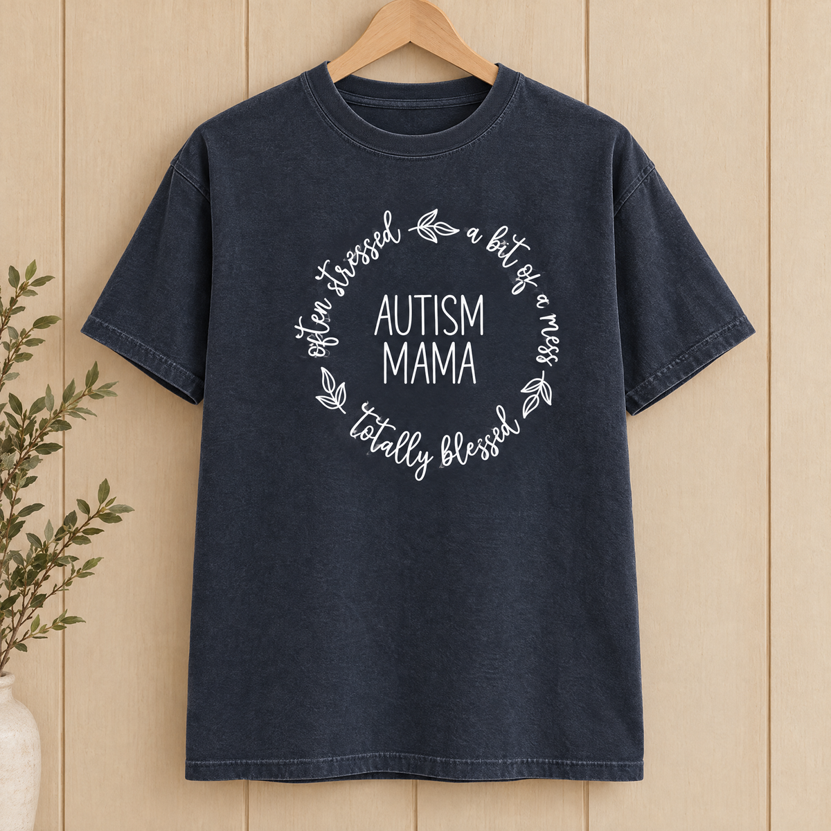 Autism Mama Comfort Colors shirt in Midnight on a wooden hanger