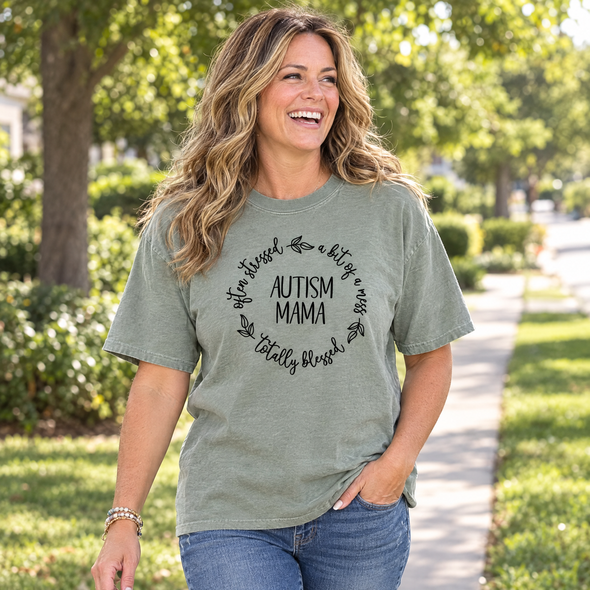 Mom wearing a Sage Comfort Colors Autism Mama shirt walking on a sunny sidewalk