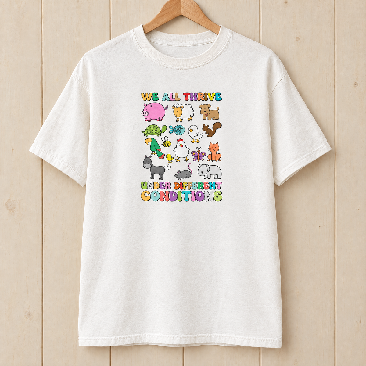 We All Thrive Under Different Conditions Comfort Colors shirt in White on a wooden hanger
