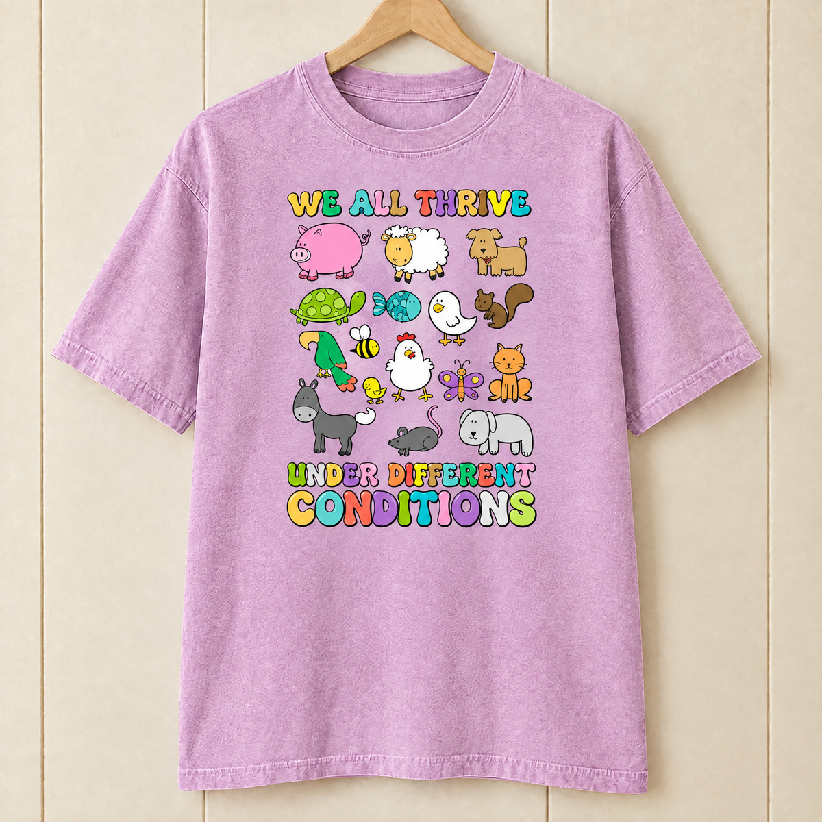 We All Thrive Under Different Conditions Comfort Colors shirt in Orchid on a wooden hanger