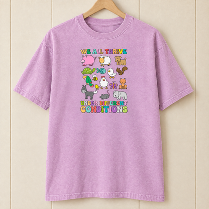 We All Thrive Under Different Conditions Comfort Colors shirt in Orchid on a wooden hanger