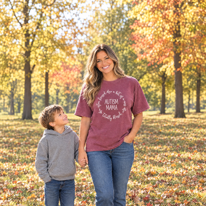 Mom wearing a Berry Comfort Colors Autism Mama shirt holding her son's hand in an autumn park