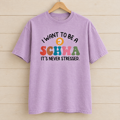 I Want To Be A Schwa shirt in Orchid Comfort Colors, on a wooden hanger