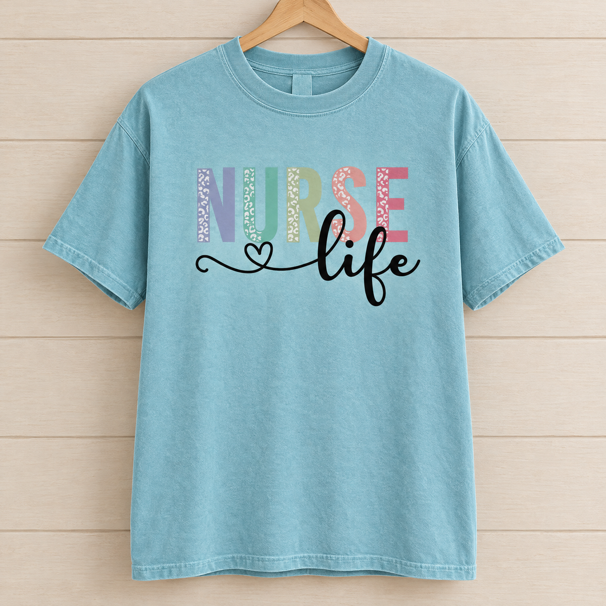 Nurse Life shirt in Lagoon Blue Comfort Colors, on a wooden hanger