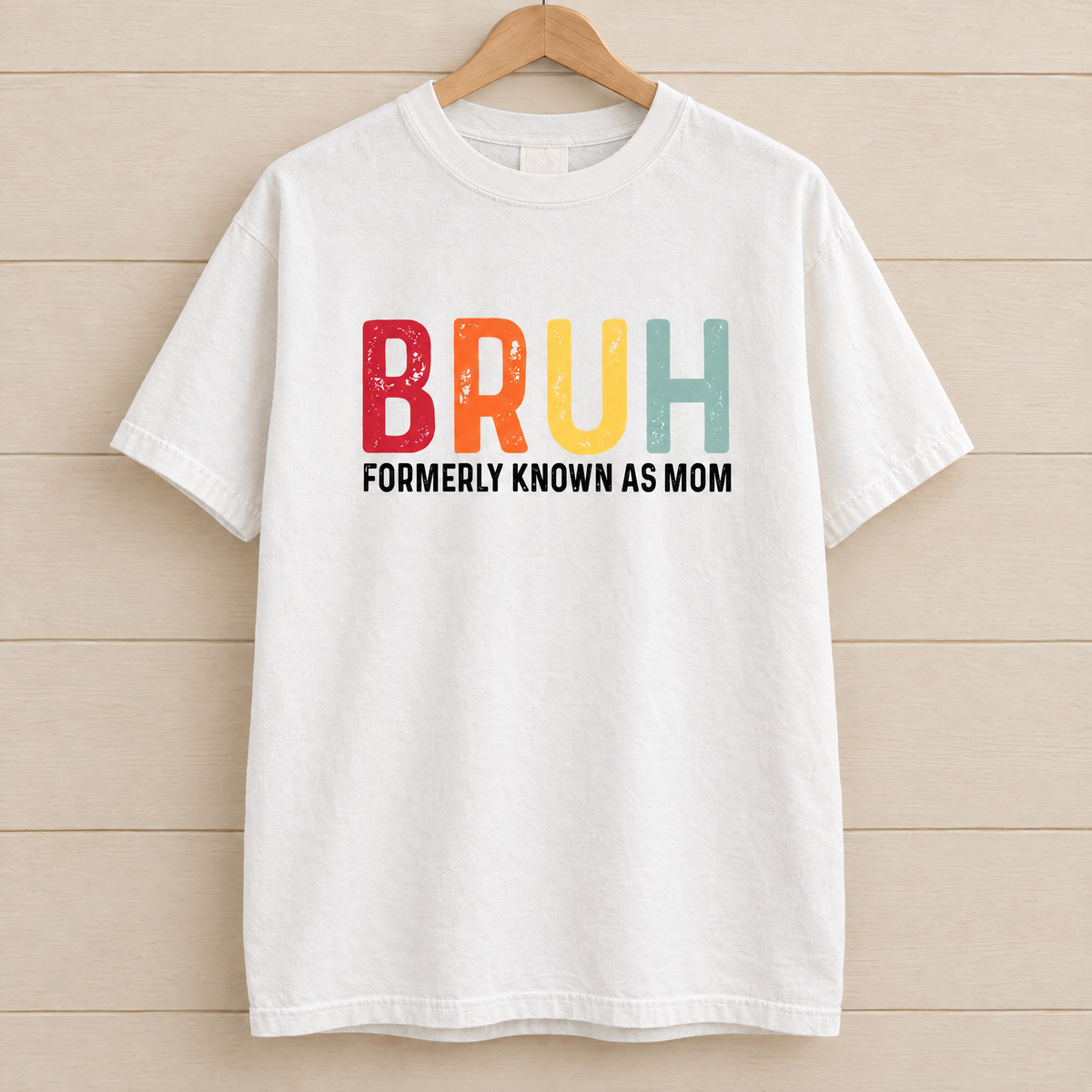 Bruh Formerly Known As Mom shirt in White Comfort Colors, on a wooden hanger