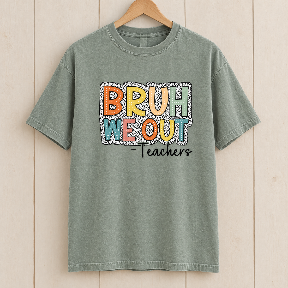 Bruh We Out Teachers shirt in Sage Comfort Colors, on a wooden hanger