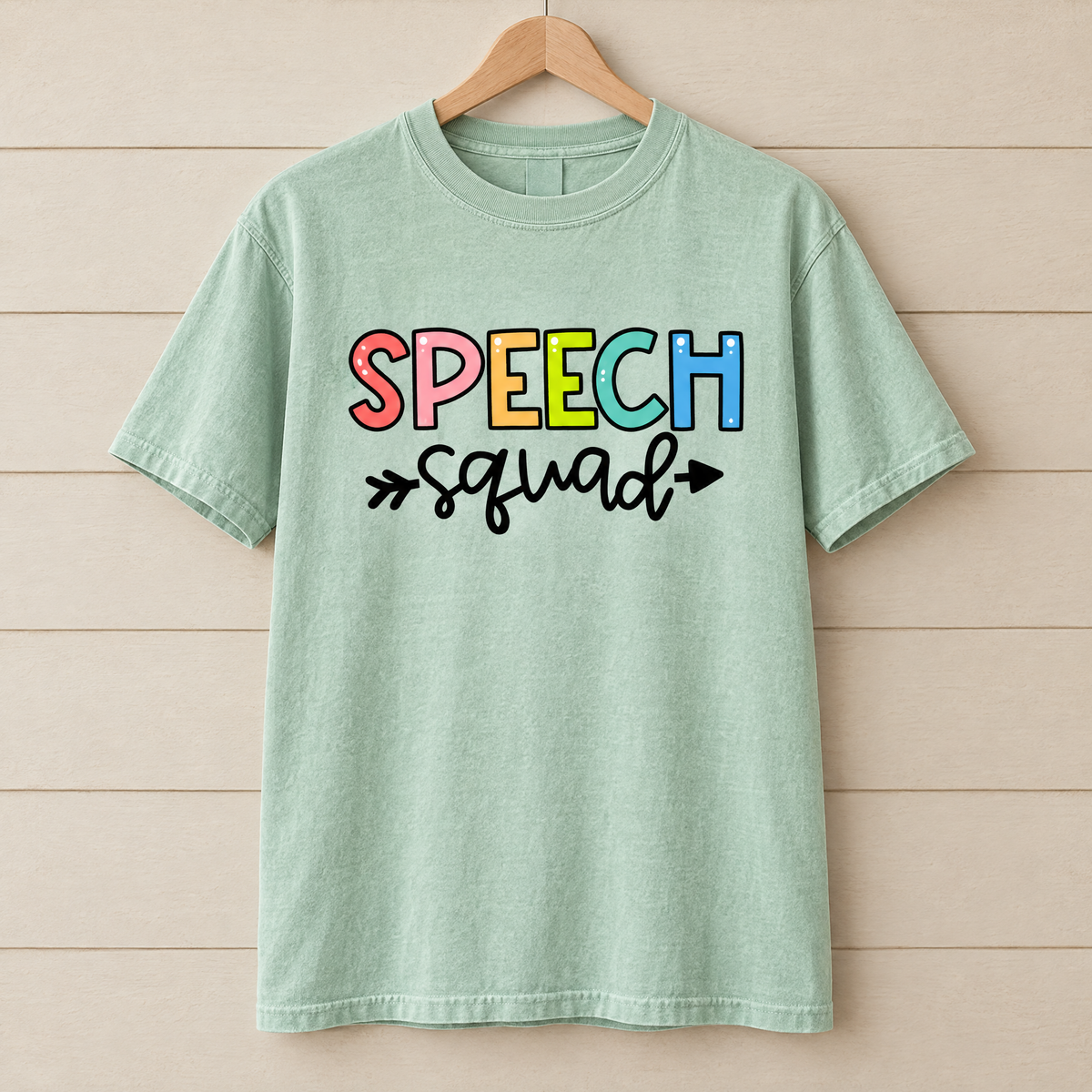 Speech Squad shirt in Light Green Comfort Colors, on a wooden hanger