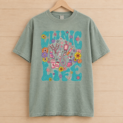 Clinic Life shirt in Sage Comfort Colors, on a wooden hanger