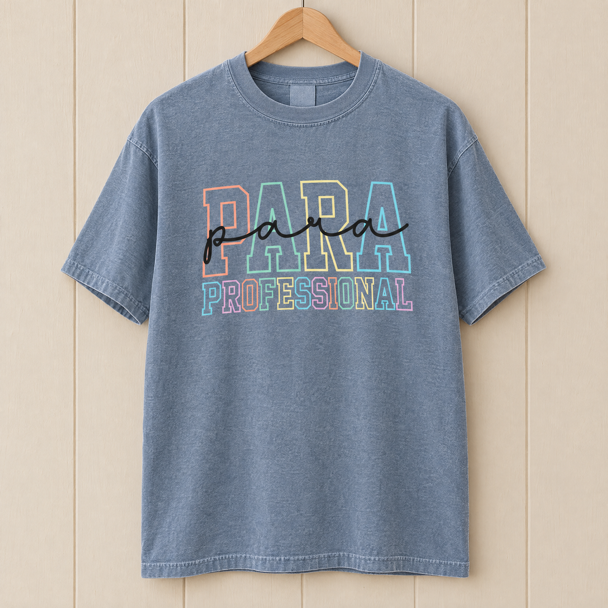 Paraprofessional shirt in Chambray Comfort Colors, on a wooden hanger