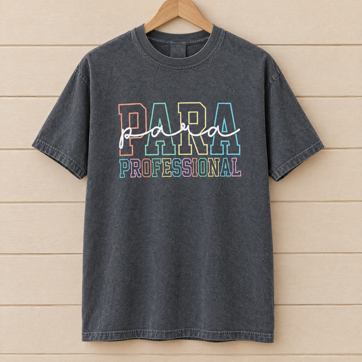Paraprofessional shirt in Pepper Comfort Colors, on a wooden hanger