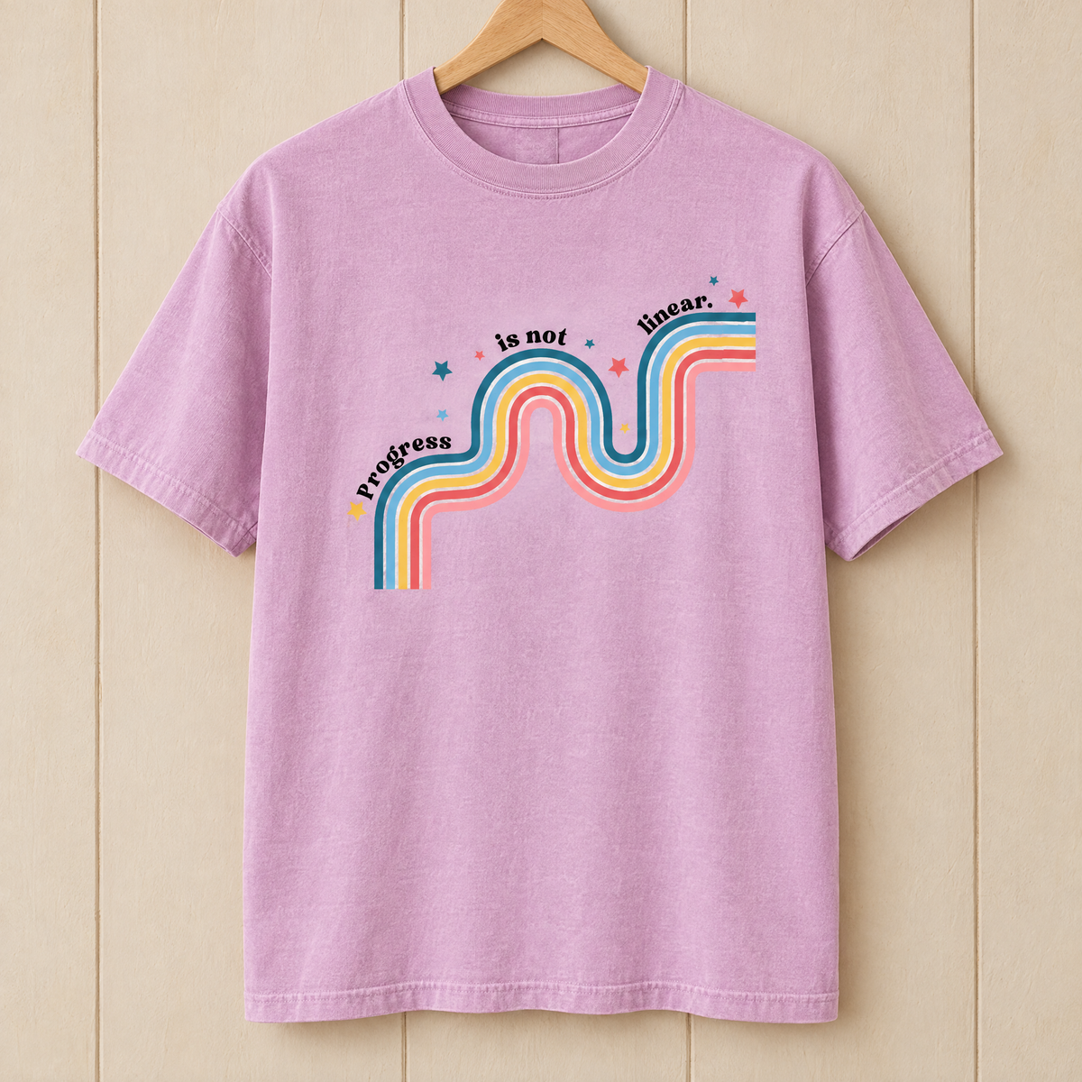 Progress Is Not Linear shirt in Orchid Comfort Colors, on a wooden hanger