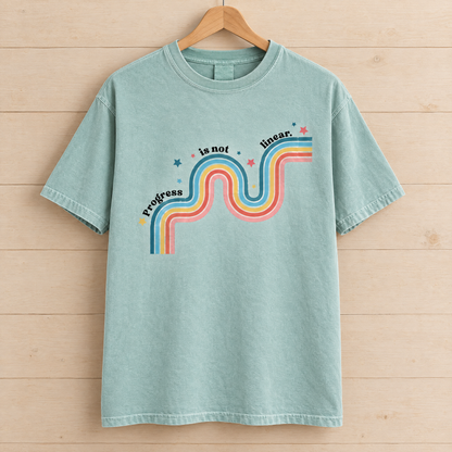Progress Is Not Linear shirt in Seafoam Comfort Colors, on a wooden hanger