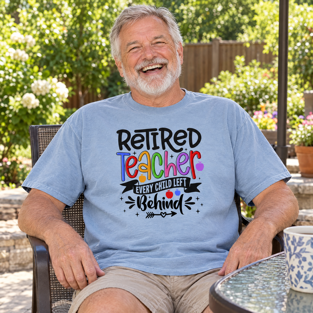 Retired Teacher shirt in Chambray Comfort Colors, worn by a seated model