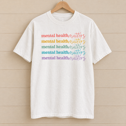Mental Health Matters rainbow shirt in White Comfort Colors on a wooden hanger