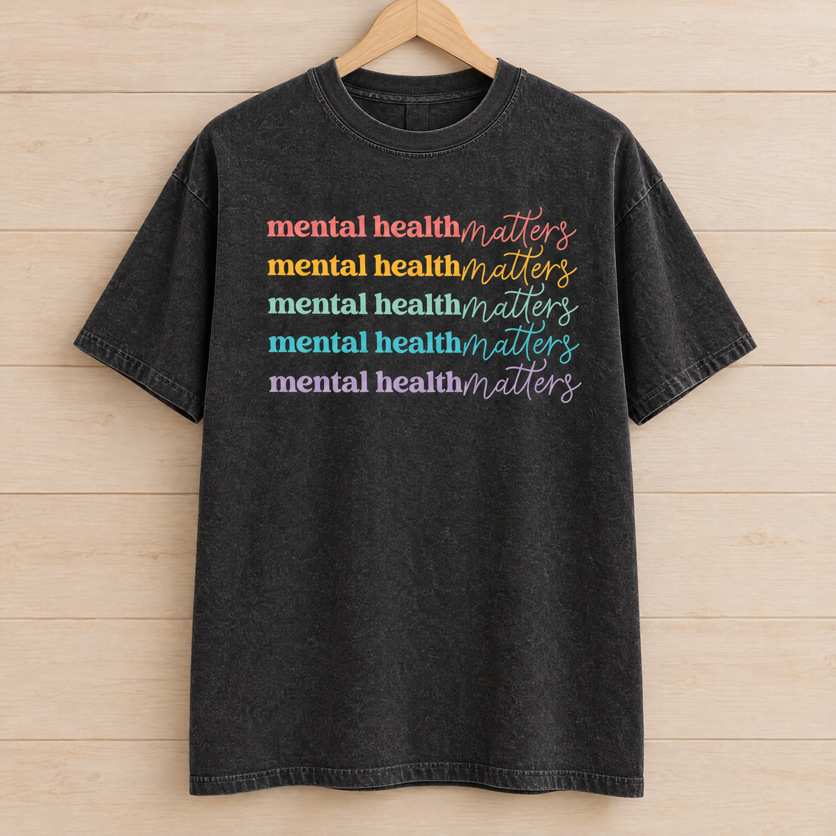 Mental Health Matters rainbow shirt in Black Comfort Colors on a wooden hanger