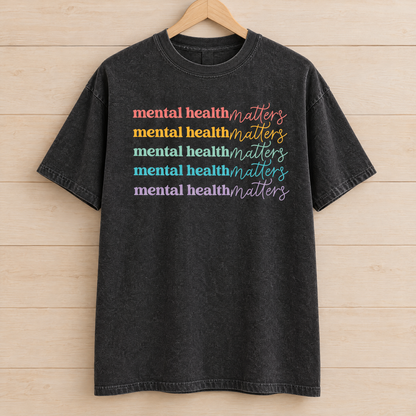 Mental Health Matters rainbow shirt in Black Comfort Colors on a wooden hanger
