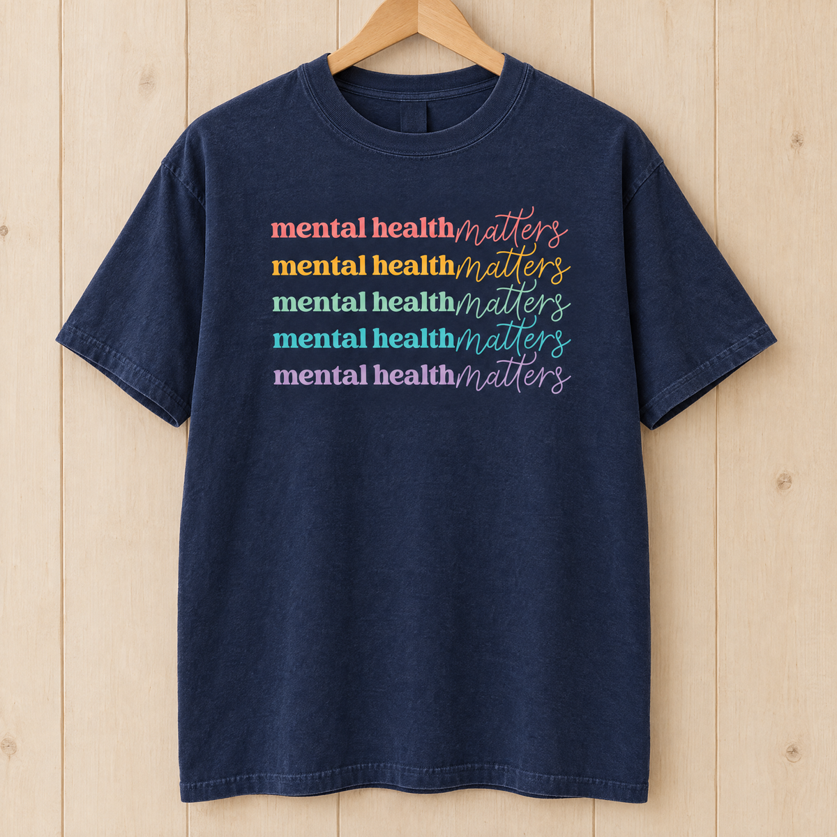 Mental Health Matters rainbow shirt in Midnight Comfort Colors on a wooden hanger