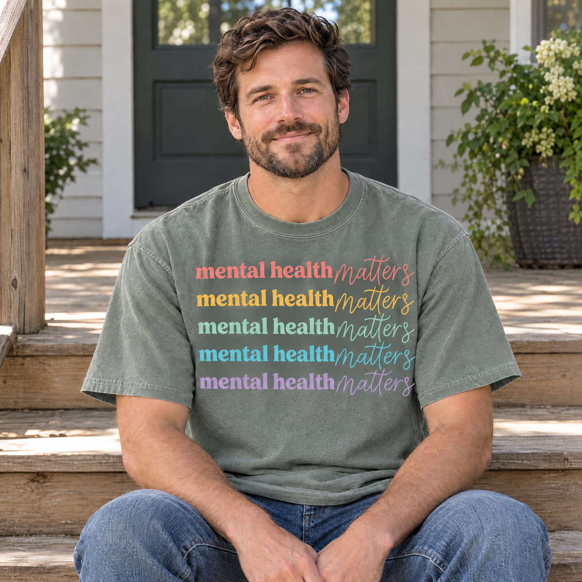 Mental Health Matters rainbow shirt in Sage Comfort Colors, man sitting on porch steps
