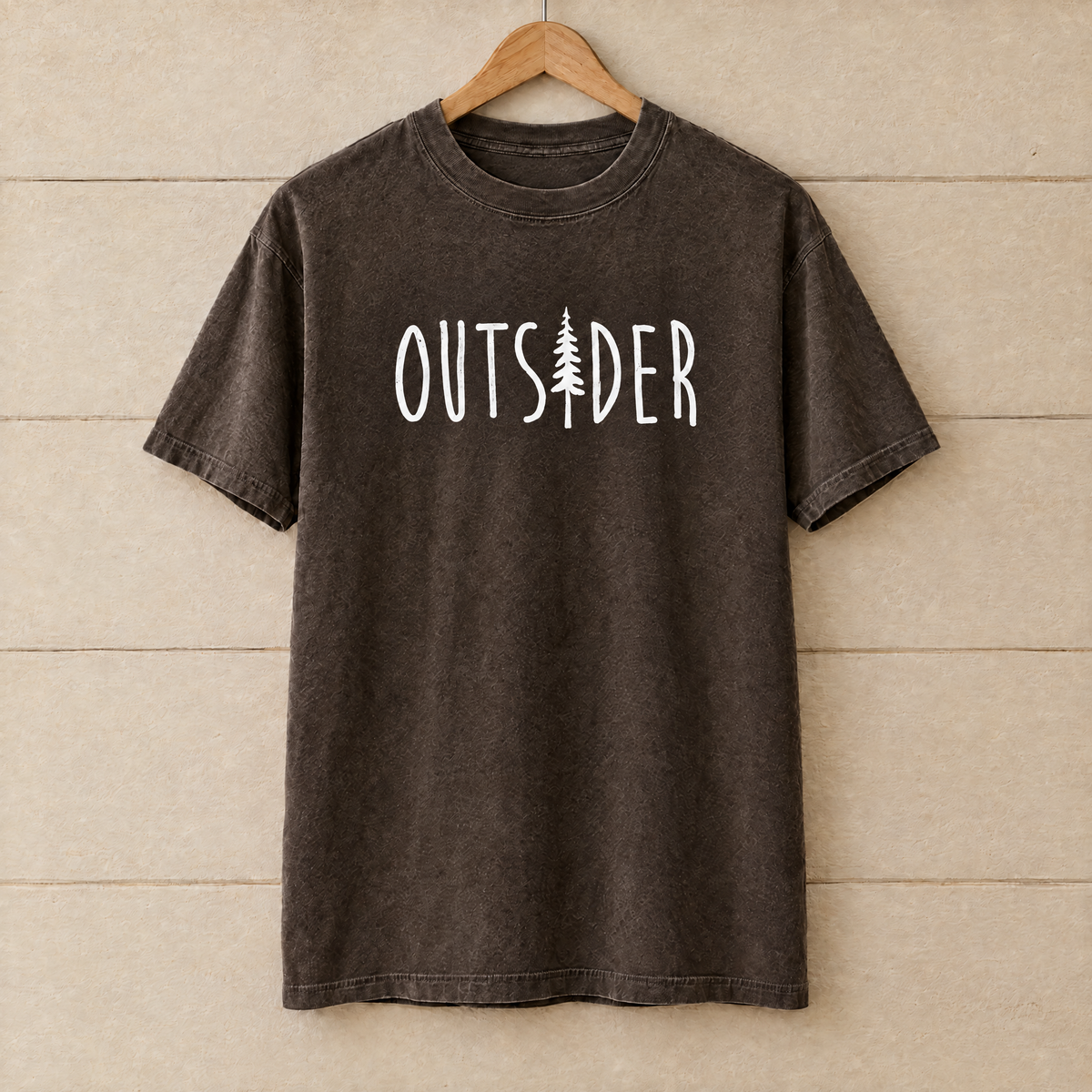Outsider camping shirt with pine tree in Espresso Comfort Colors on a wooden hanger
