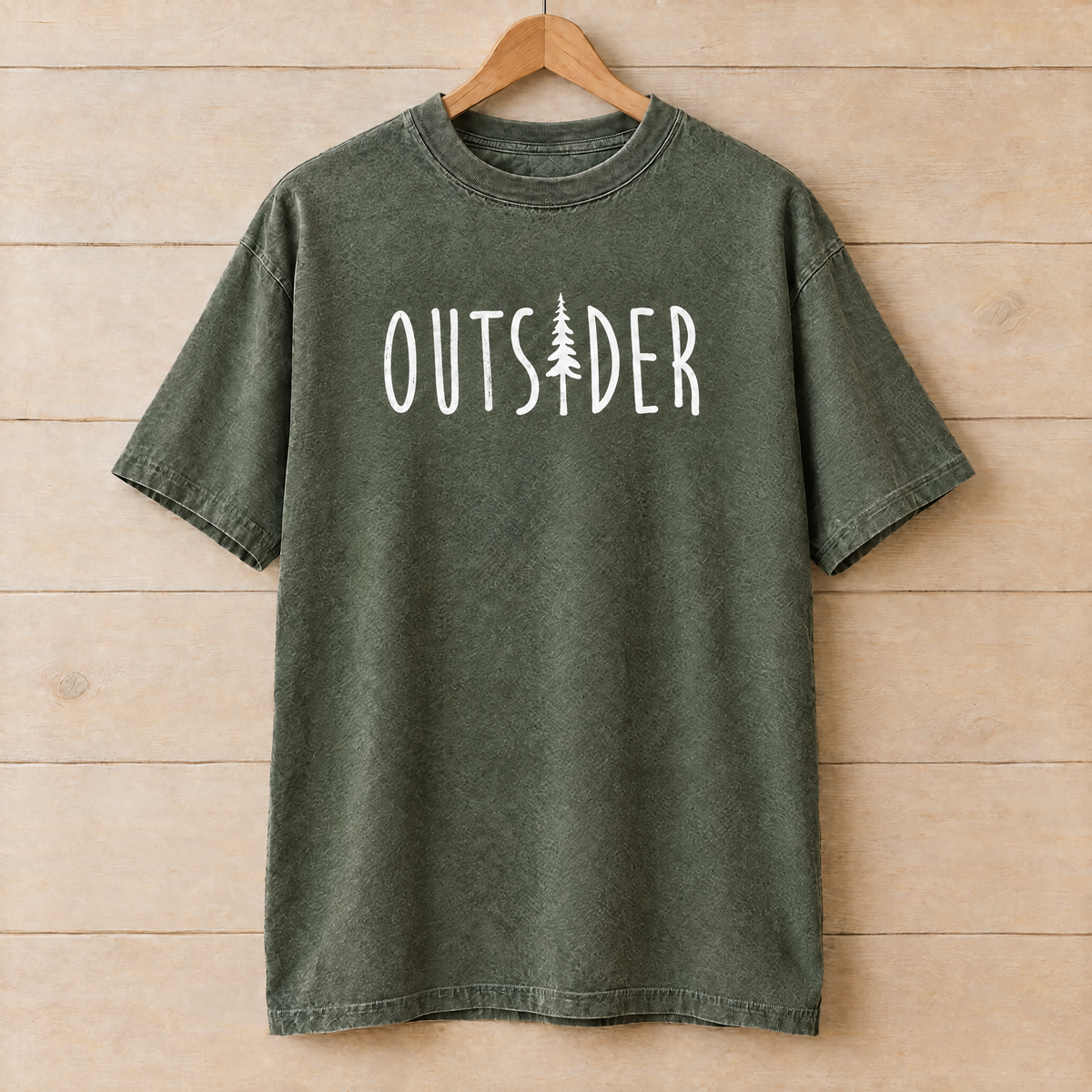 Outsider camping shirt with pine tree in Moss Comfort Colors on a wooden hanger