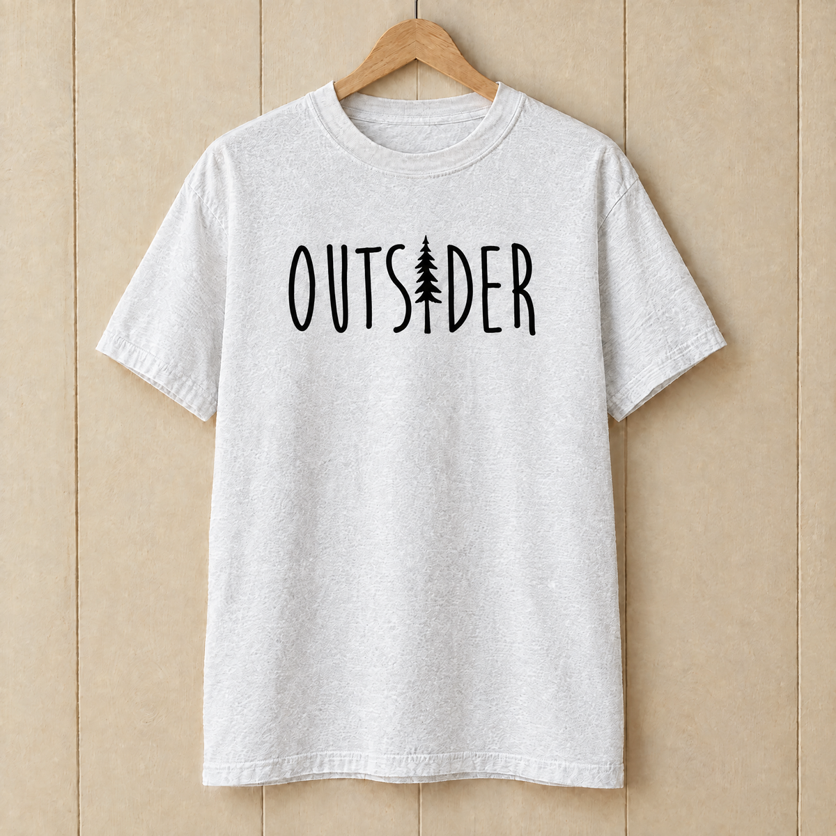 Outsider camping shirt with pine tree in White Comfort Colors on a wooden hanger