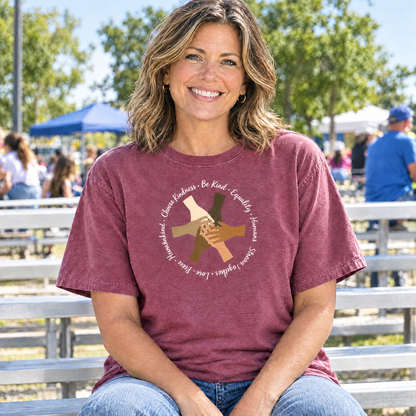 Choose Kindness diverse hands circle shirt in Berry Comfort Colors, woman sitting on bleachers at a community event