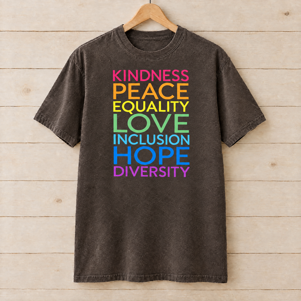Kindness Peace Equality Love rainbow words shirt in Espresso Comfort Colors on a wooden hanger