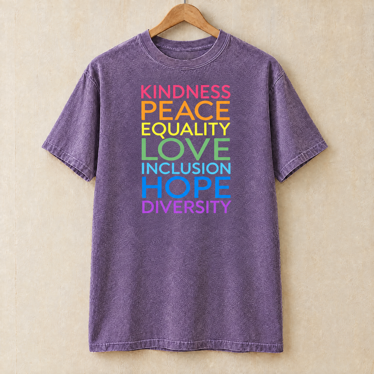 Kindness Peace Equality Love rainbow words shirt in Grape Comfort Colors on a wooden hanger
