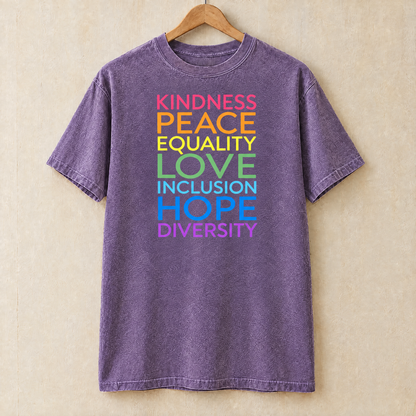 Kindness Peace Equality Love rainbow words shirt in Grape Comfort Colors on a wooden hanger