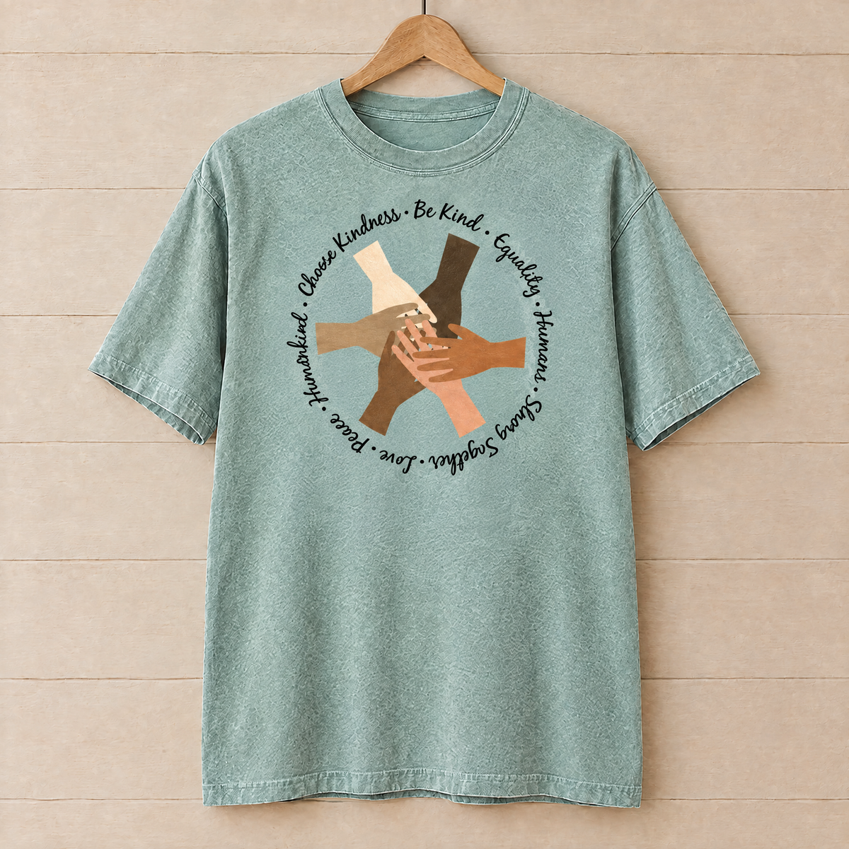 Choose Kindness diverse hands circle shirt in Seafoam Comfort Colors on a wooden hanger