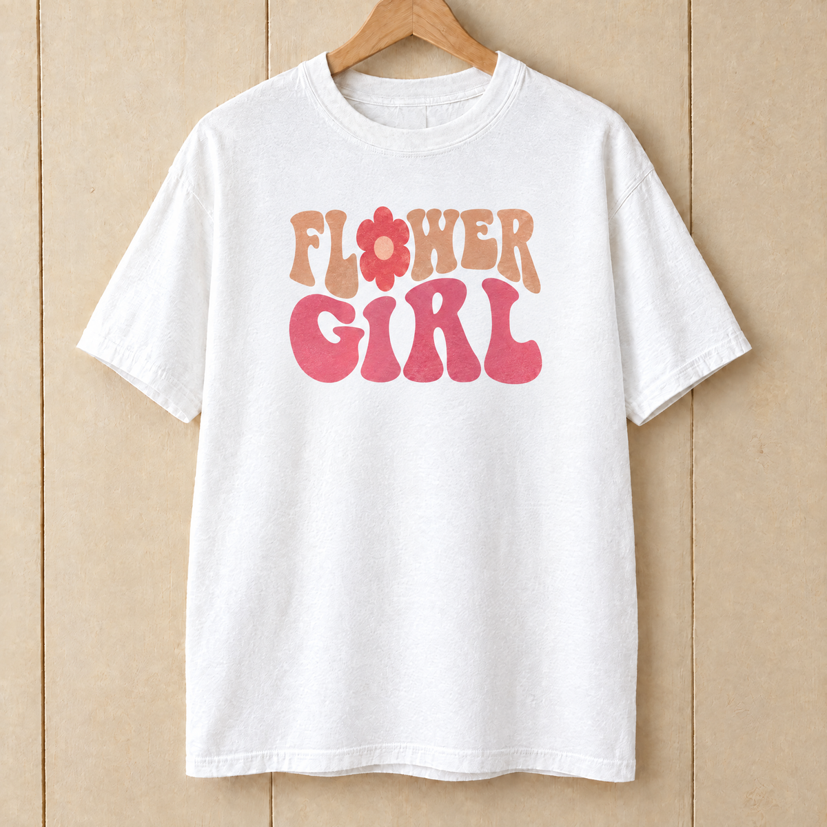 Flower Girl retro groovy shirt in White Comfort Colors on a wooden hanger