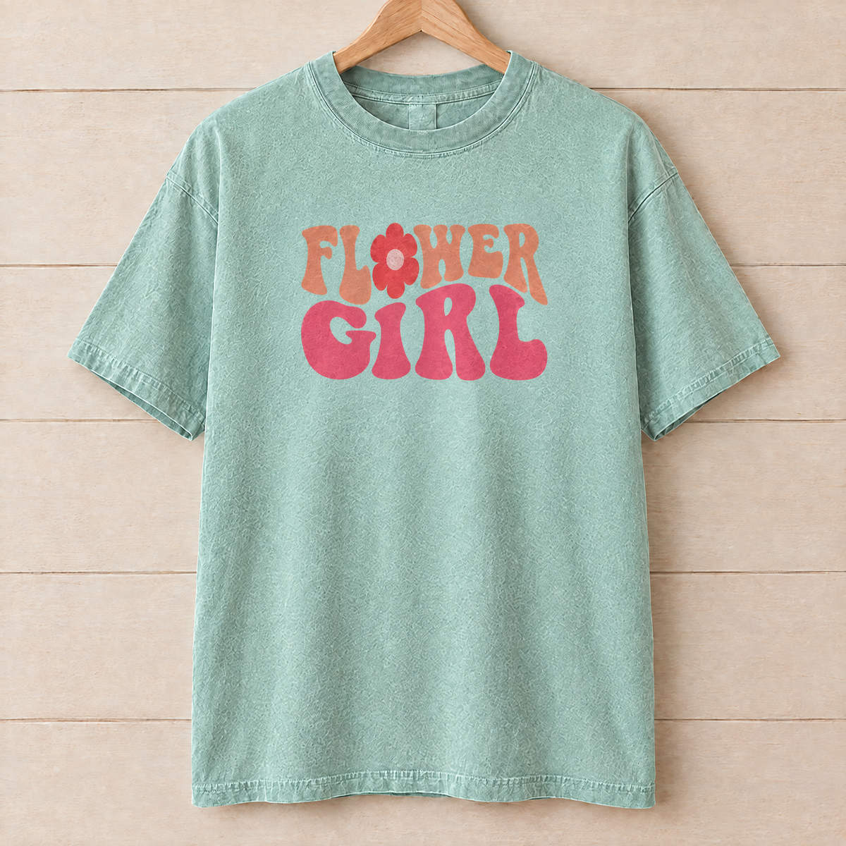 Flower Girl retro groovy shirt in Seafoam Comfort Colors on a wooden hanger