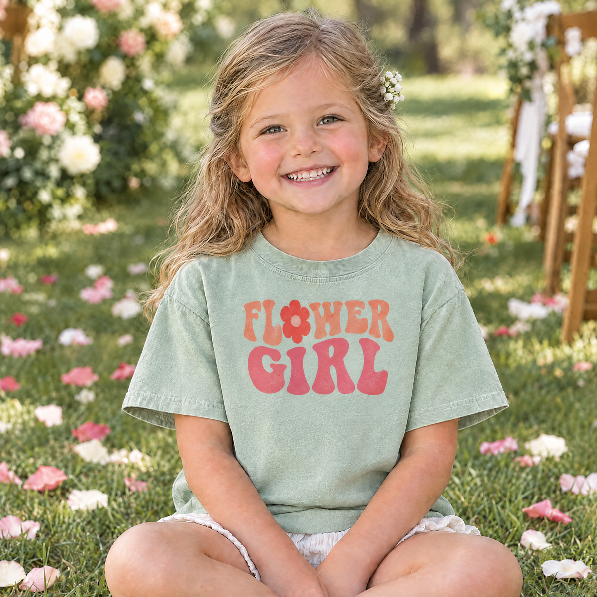 Flower Girl retro groovy shirt in Light Green Comfort Colors, little girl sitting on the grass at an outdoor wedding