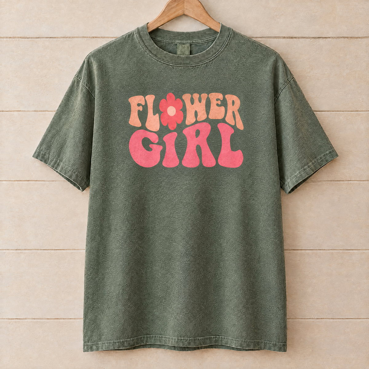 Flower Girl retro groovy shirt in Moss Comfort Colors on a wooden hanger