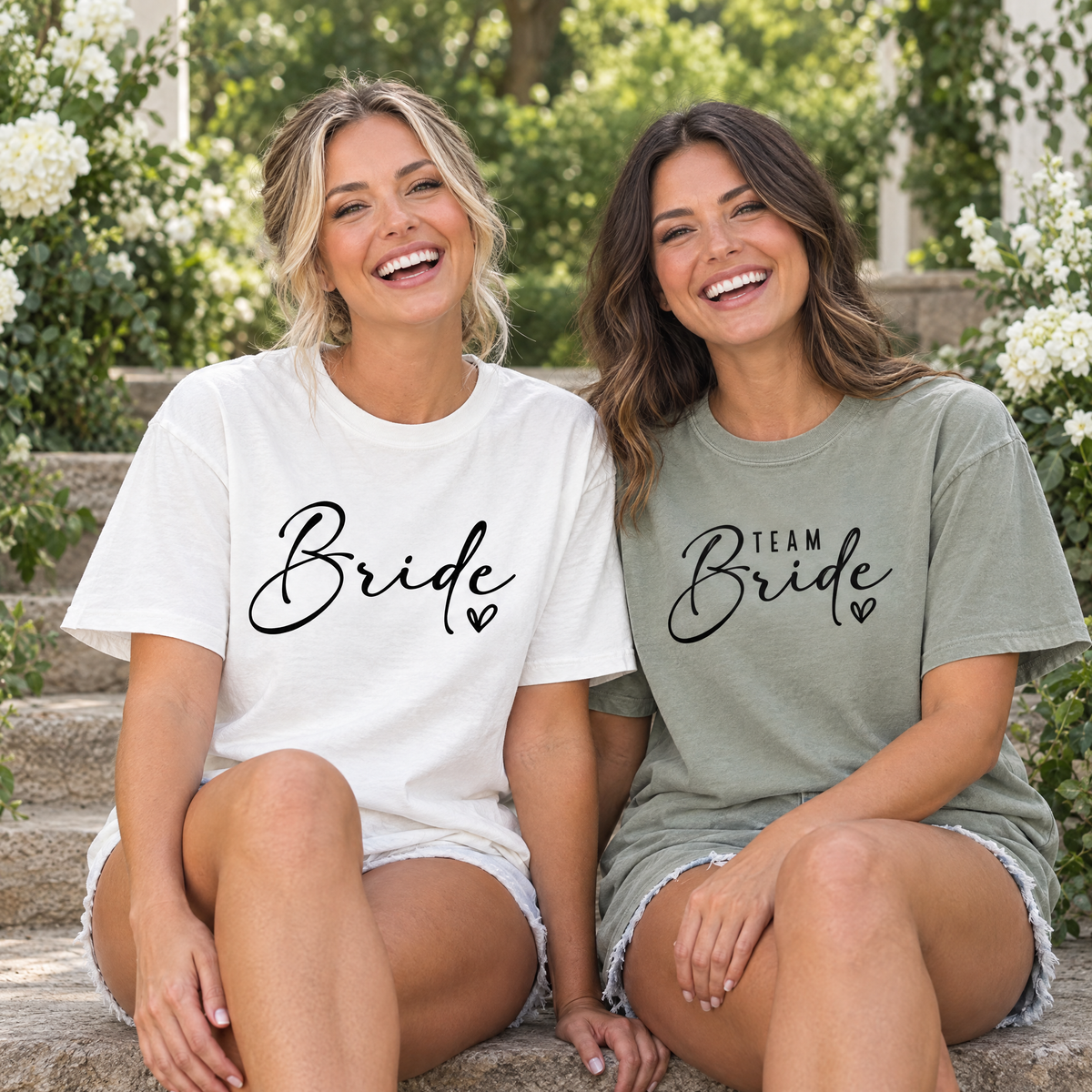Bride in a White Bride shirt and maid of honor in a Sage Team Bride shirt sitting on garden venue steps