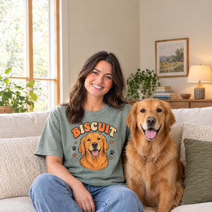 Custom pet portrait shirt, woman on a sofa with her golden retriever wearing a Sage Comfort Colors tee with a cartoon portrait of her dog named Biscuit