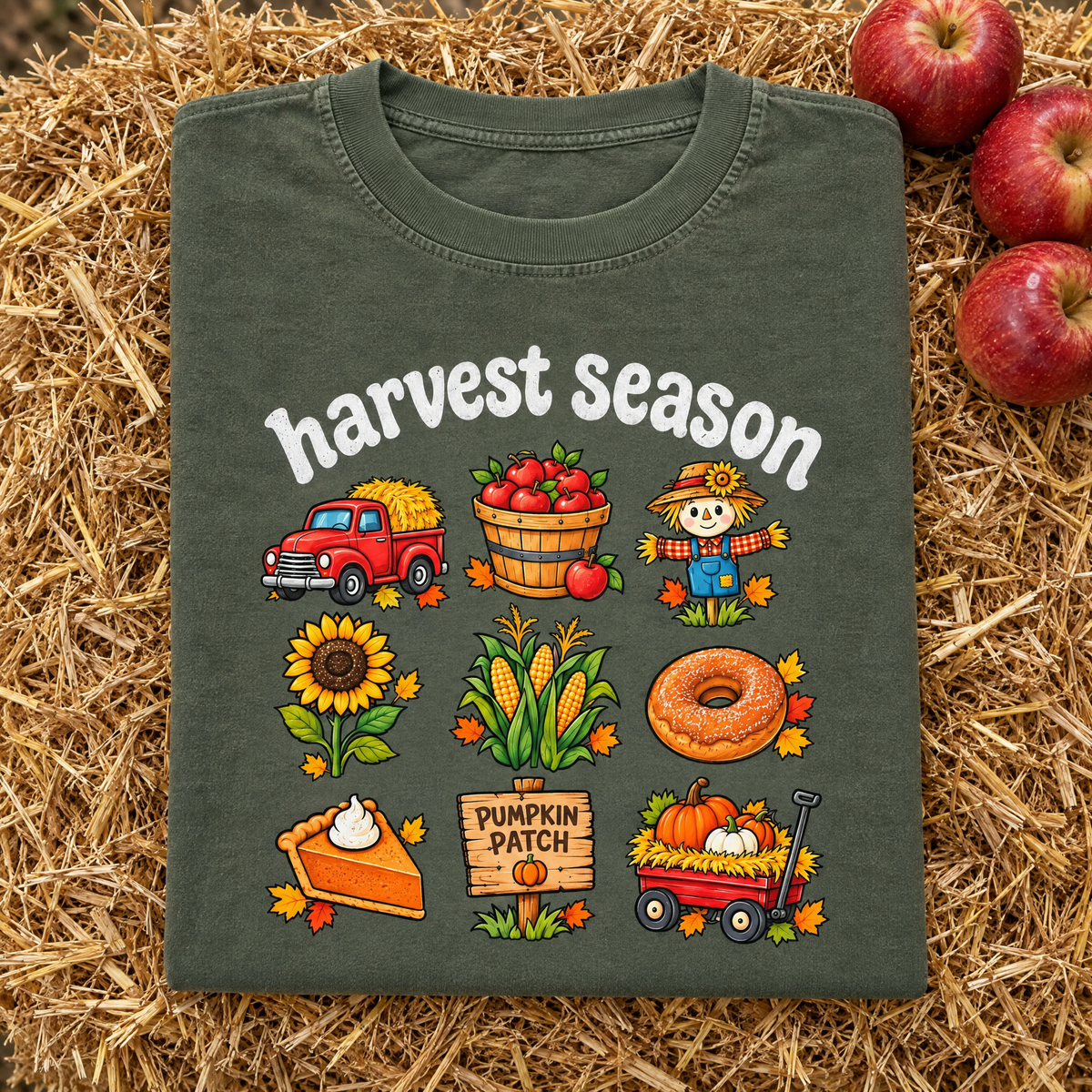 Pumpkin patch Harvest Season tee in Moss, folded on a hay bale with apples