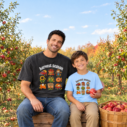 Dad in a Black Comfort Colors Harvest Season shirt and son in a Light Blue youth Harvest Season tee in an apple orchard