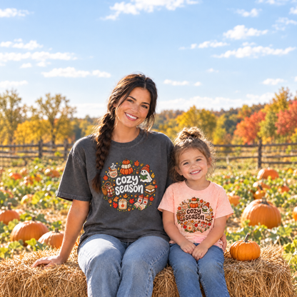 Mom in a Pepper Comfort Colors Cozy Season shirt and toddler in a Heather Peach toddler Cozy Season tee at a pumpkin patch