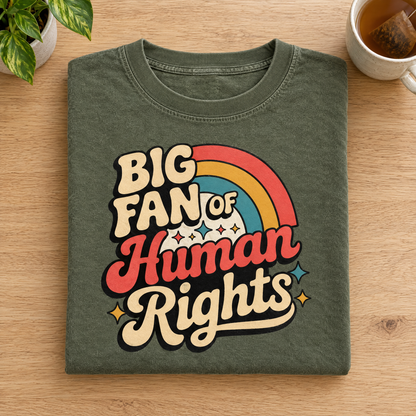 Human rights retro groovy tee in Moss, folded next to a plant and tea