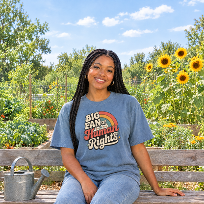 Woman wearing Blue Jean Comfort Colors Big Fan of Human Rights shirt in a community garden