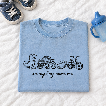 Chambray light blue In My Boy Mom Era shirt folded next to kids sneakers and a sippy cup